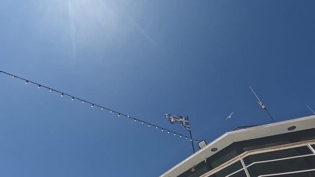 Greek ferry boat with national flag flying against brilliant clear blue sky. Perfect maritime scene showcasing Greek island transportation and nautical travel atmosphere.