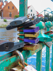 Colorful love locks attached to an old green metal bridge railing