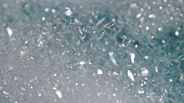 Soap bubbles and droplets on shiny surfaces captured in macro, ideal for illustrating cleanliness, washing rituals, or sterile environments.