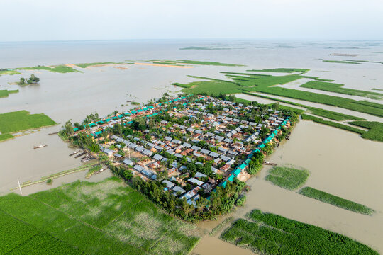 Sariakandi, Bangladesh - 15 July 2019: Aerial view of a village surrounded by floodwaters, where the rooftops contrast with the inundated landscape, showcasing the resilience amidst the deluge.