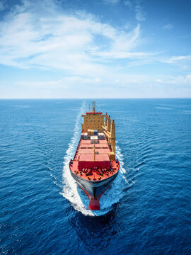 Aerial front view of a universal bulk carrier cargo vessel traveling with high speed over blue sea with copy space