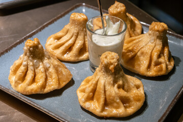 Plate of golden fried khinkali, a traditional Georgian dumplings with a dipping sauce