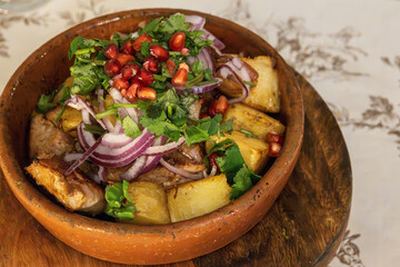 Ojakhuri, a popular Georgian dish, potatoes and meat fried together, seasoned with herbs, onions, and topped with pomegranate seeds. Served in a clay pot.
