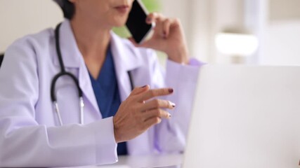 Asian adult female doctor providing telehealth consultation online using smartphone and laptop in modern clinic office - Powered by Adobe