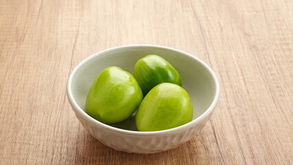 Fresh green tomatoes served on white bowl
