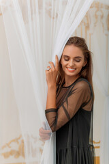 Smiling woman with engagement ring behind curtain