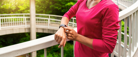 Fit female athlete looking at smart watch fitness tracker while exercising outside