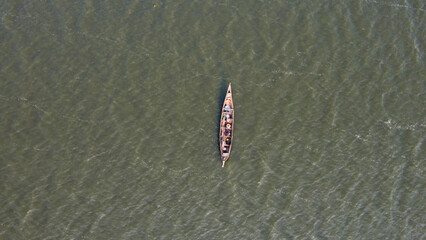 Aerial View of a Wooden Boat Sailing on Calm, Olive-Green Waters in Southeast Asia