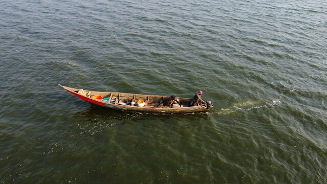Fishing Expedition: Men Sailing on Wooden Boat with Motor across a Dark Lake