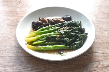 fried Kailaan Chinese kale and black mushroom dressing oyster sauce with chop garlic on plate
