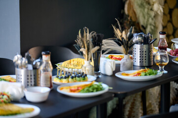 Chic dining setup featuring plates of vibrant salads and gourmet dishes. Ambient lighting enhances elegant decor with rustic touches. Cozy atmosphere invites indulgence