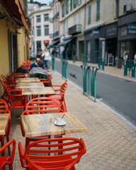Charming Street Side Cafe with Red Chairs Along a Quiet European City Road Inviting Relaxation and Leisure
