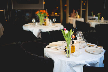 Elegant Restaurant Dining Setting with Fresh Tulip Centerpiece and Romantic Ambiance Under Soft Lighting
