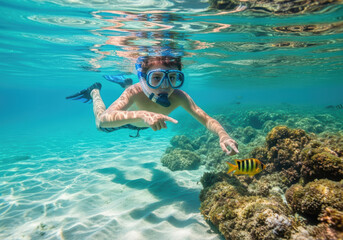 Fototapeta premium A child snorkels and points to a fish in a clear tropical sea, symbolizing discovery, joy, and summer adventure