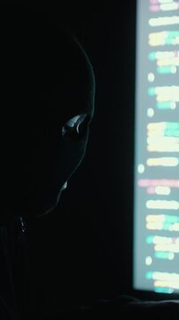 Close-up Hacker in balaclava with an obscured face is stealing data, representing cybercrime, hacking, dark web activity, and online security threats. Cyber Security concept.
