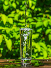 Dynamic Low-Angle Shot of Mineral Water Splashing in Glass Tumbler with Vibrant Green Background

