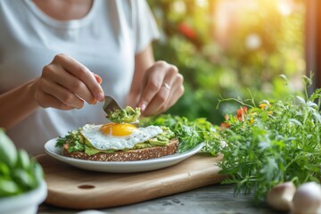 Woman adding avocado to fried egg on toast for healthy breakfast