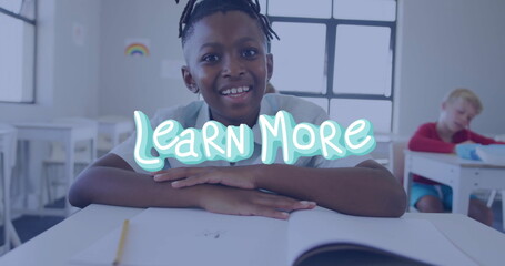 Leaning African American boy folding arms over notebook at desk in classroom, with rainbow sticker