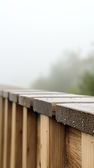Close-up of a wooden railing adorned with glistening rain droplets, set against a soft, ethereal mist, evoking a tranquil and contemplative outdoor scene.