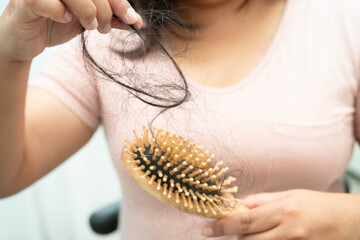 Asian woman have problem with long hair loss attach to comb brush.