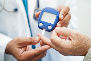 Asian doctor using digital glucose meter for check sample blood sugar level to treatment diabetes.