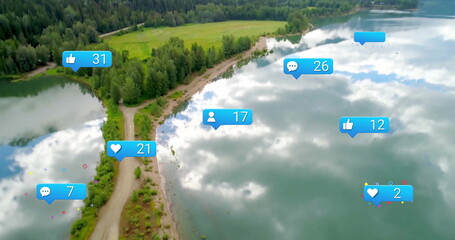 Showing grassy peninsula with dirt path extending into calm lake, with floating social media icons