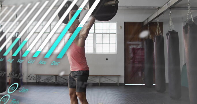 Pressing man in red tank top lifting barbell overhead in gym with punching bags, chart overlay
