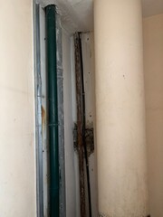 Old building structure with exposed pipes and columns in narrow space