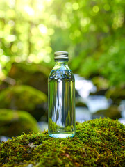 Artistic Photo of Transparent Mineral Water Bottle with Dreamy Light Refractions and Lush Green Background