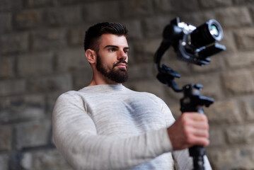A man stands confidently in an urban environment, skillfully using a gimbal stabilizer while...