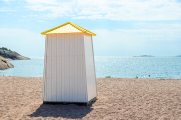 Sunny sandy beach in Hanko, Finland, with colorful iconic changing cabin, hut, booth, a cheerful...