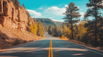 Naklejka premium Scenic Mountain Road with Lush Trees and Vibrant Blue Sky