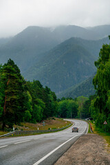 a car is driving along a mountain road in the Caucasus to Arkhyz, among the mountains and clouds before the rain

