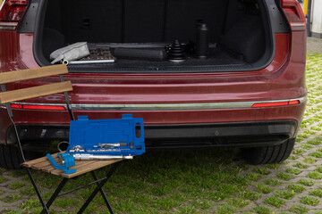 Car repair kit with tools next to open SUV trunk in outdoor setting