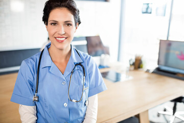 Stethoscope hanging on chair by light wood desk with dual monitors near bright window, copy space