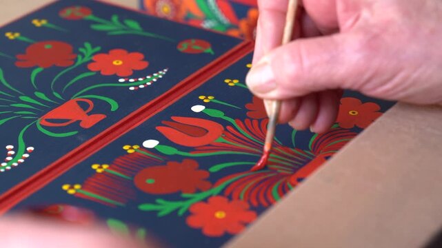 Close-up of hand painting vibrant floral pattern on Maty&oacute; decorative panel
