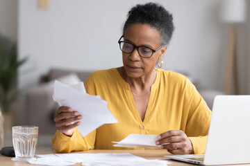 Middle-aged African-American woman creating email templates for customer service follow-ups, testing tone and format