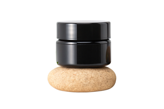 Single black cosmetic container balanced on one smooth stone in minimalist spa setting, isolated on a transparent background