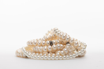 A pile of lustrous white pearl necklaces on a clean white background, showcasing classic elegance and timeless beauty
