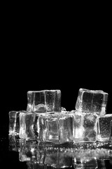 A close-up shot of several clear ice cubes reflecting on a dark, reflective surface, 