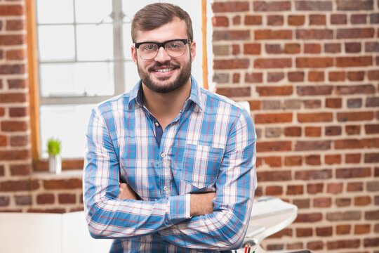 African American man standing in loft office by white desk holding colored pens and succulent - Powered by Adobe