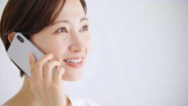 スマホで通話中の女性：電話で問い合わせ：通信