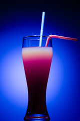 A gradient-colored drink in a tall glass, featuring a blend of orange and red hues, 
