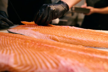 Chef slicing fresh salmon fillet with precision on a cutting board in a professional kitchen....
