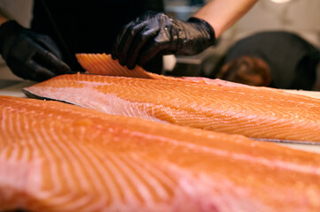 Chef slicing fresh salmon fillet with precision on a cutting board in a professional kitchen....