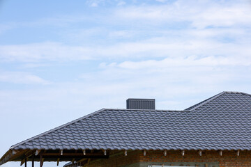 Fototapeta premium A residential building featuring a modern roof design with textured shingles under a clear blue sky during daytime