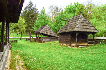 Obraz premium Traditional Romanian wooden houses and farm buildings at Romulus Vuia Ethnographic Park, Cluj-Napoca - authentic folk village showcasing rural heritage and historical architecture in open air museum
