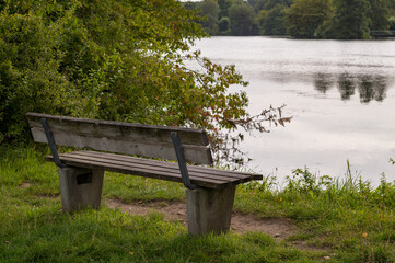Empty bench overlooking serene lake on cloudy day