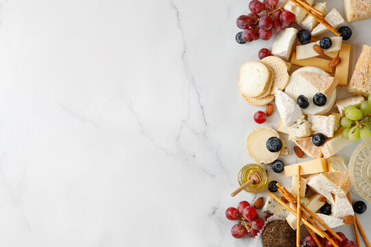 Cheese banner, assortment of traditional cheese, brie, gorgonzola, lambert, livaro, raclette. Antipasto, corner border, copy space. Marble white background, top view.