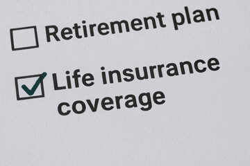 Fototapeta premium Life insurance coverage checked with retirement plan option on paper representing financial security with life insurance for retirement planning